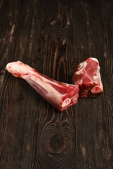 Overhead view of raw deer shank over dark wooden background