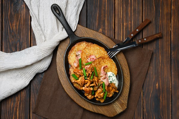 Top view of potato pancakes with chanterelles and pork in cast iron skillet