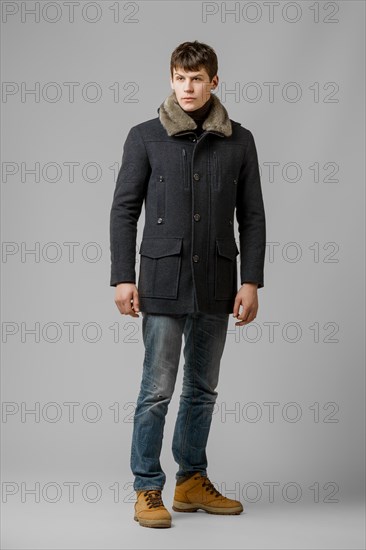 Full length portrait of handsome man in warm winter coat posing in studio