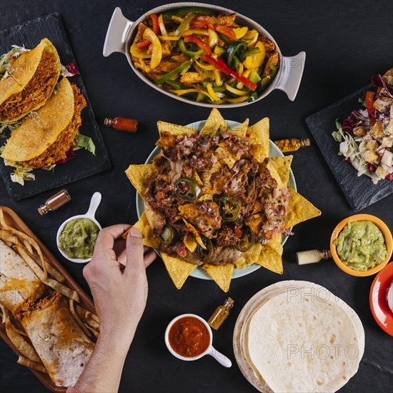 Crop hand taking nachos from plate