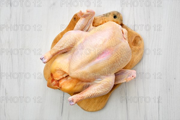 Fresh raw whole farm chicken on wooden cutting board