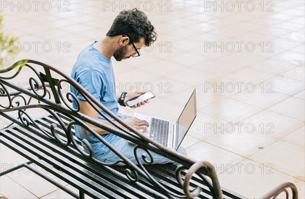 Entrepreneur man working with laptop and cellphone in a park. Freelance man working with laptop while using phone