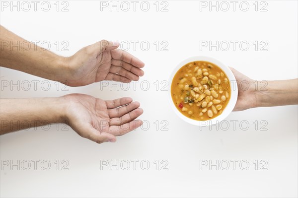 Hand giving soup bowl needy person