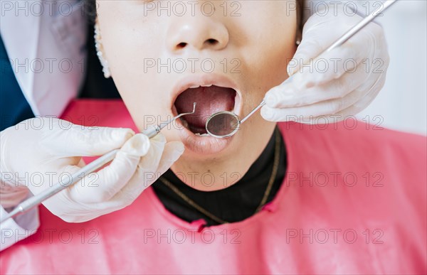 Dentist checking patient mouth with dental mirror. Close-up of patient checked by dentist