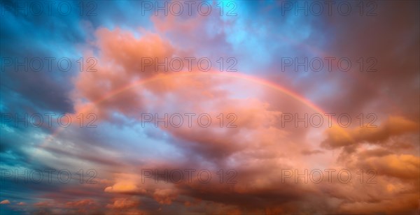 Rainbow in atmospheric sky with storm clouds at sunset