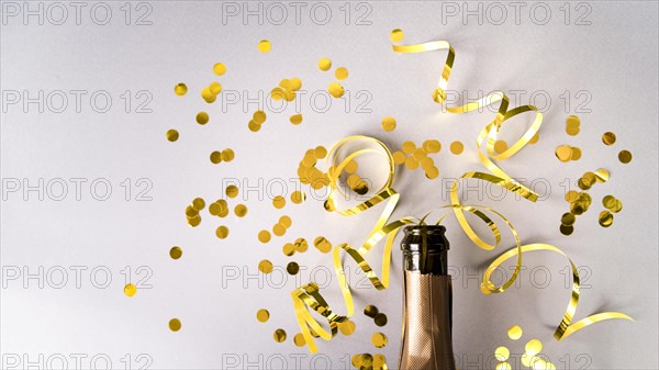 Champagne bottle with golden confetti streamers white background