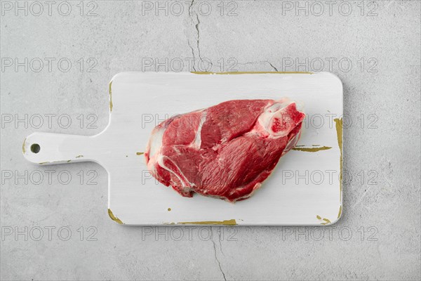 Top view of raw lamb leg cut as a steak. Slice of shank on white cutting board