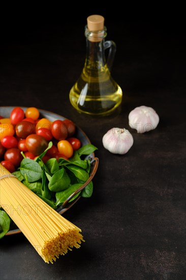 Low key photo of bunch of raw spaghetti with spinach