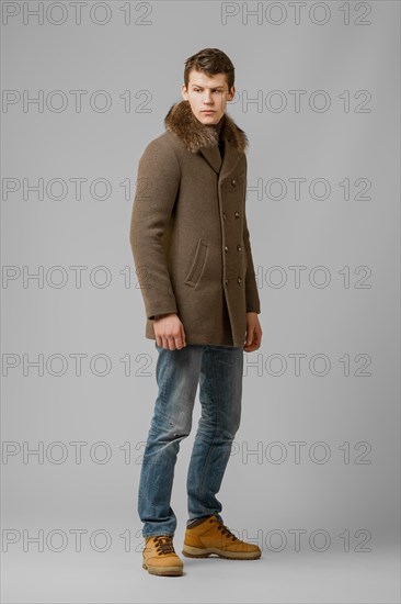 Full length portrait of handsome man in warm winter coat posing in studio