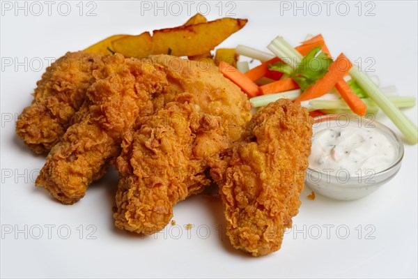 Buffalo chicken wings with fried potato and carrot and celery sticks on a plate