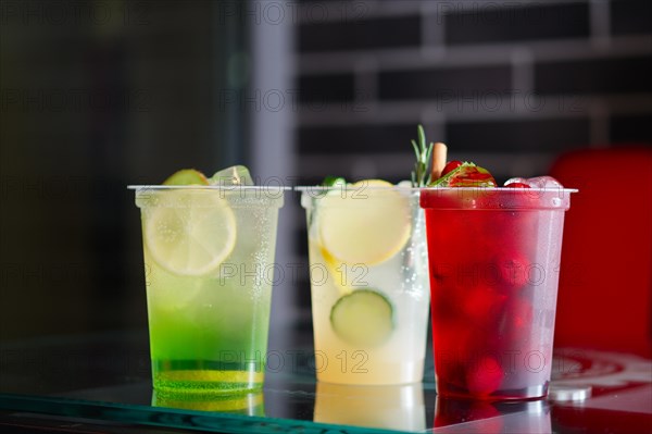 Three glasses with cool lemonade on glass table