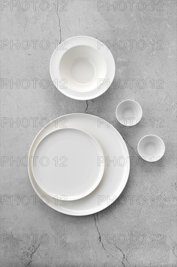 Overhead view of white tableware on grey background