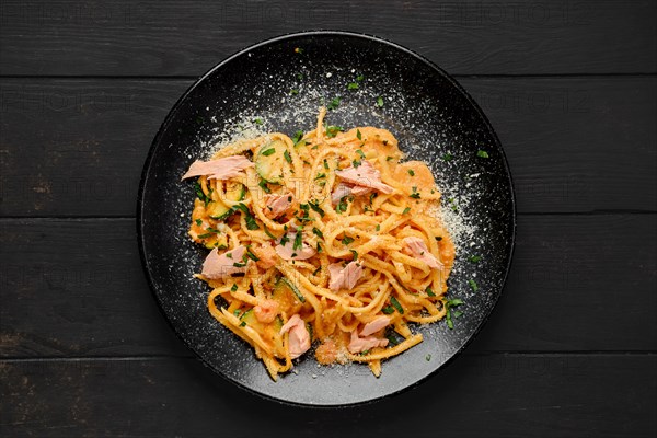 Top view of pasta with salmon and zuccini with grated parmesan on a plate