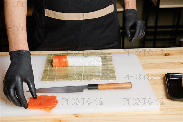 Hands of chef making salmon rolls