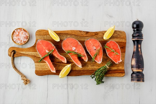 Overhead view of raw trout steaks on wooden cutting board ready for cooking