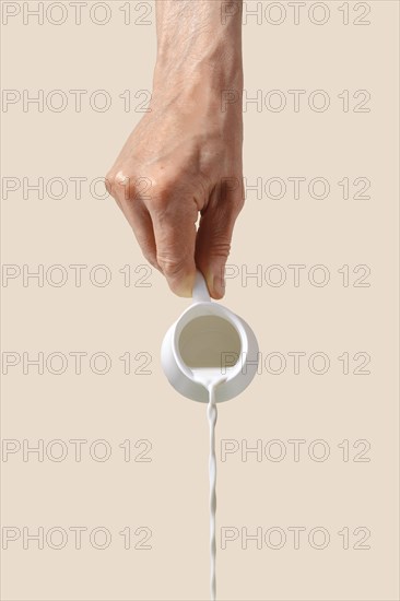 Hand holds milk pot and pouring it