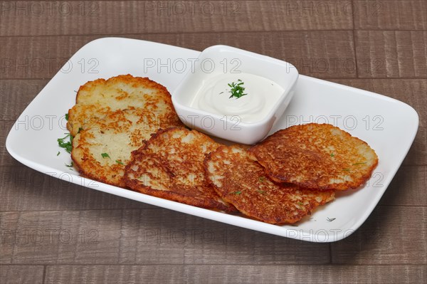 Traditional belorussian potato pancakes with machanka sauce on wooden table