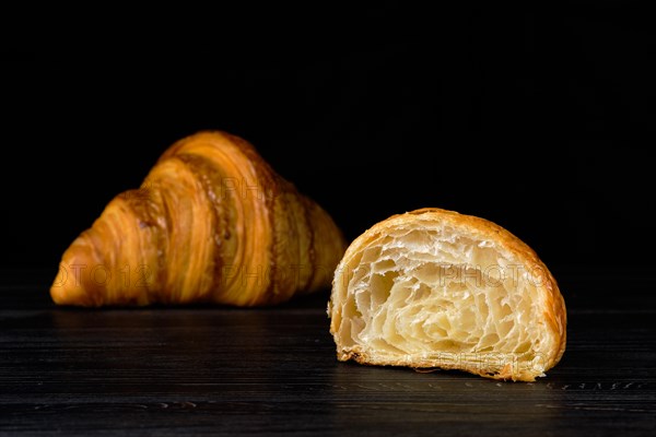 Fresh golden croissant on black table