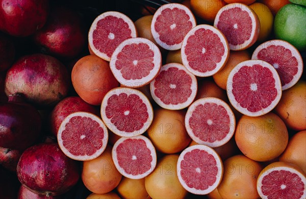 Cut in halves grapfruits alongside pomegranates on display