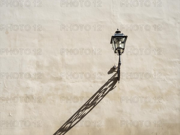 Lamp casting shadows on a house wall