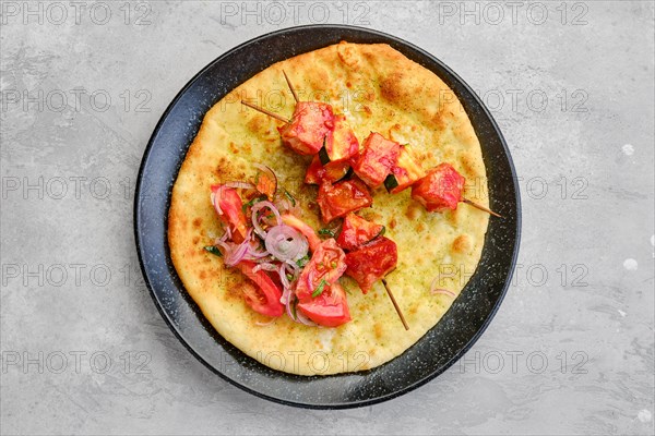 Top view of shashlik served on tortilla with tomato and red onion