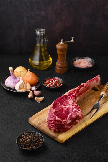 Raw beef cowboy steak with spice and seasoning ready for cooking