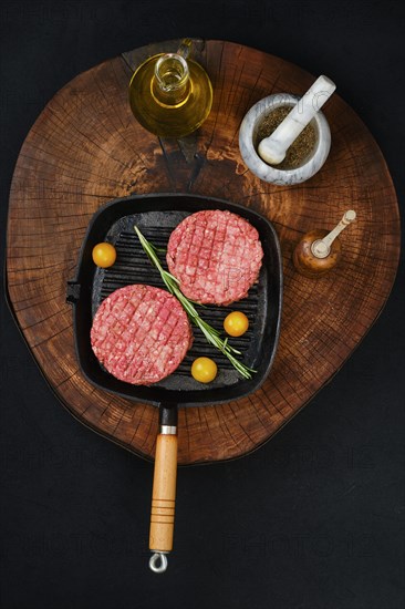 Top view of raw beef burger cutlet on cast iron pan