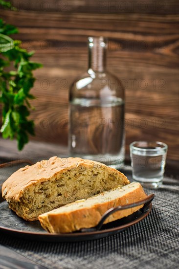 Homemade bread with pumpkin seeds and frozen vodka on rustic background