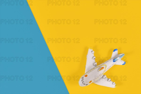 Small model airplane in corner of yellow and blue background