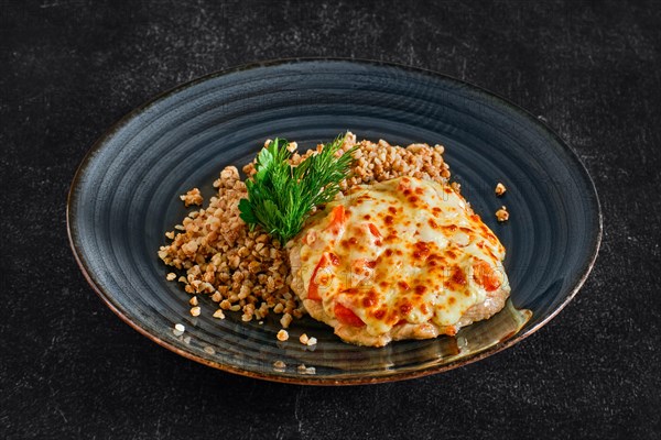 Chopped pork meat baked with cheese and tomato served with buckwheat porridge