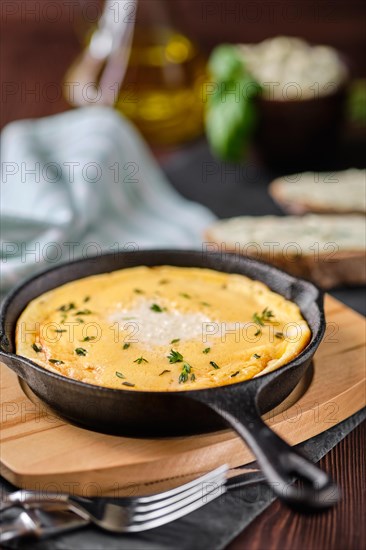 Omelette in cast iron skillet with bread and herbal butter