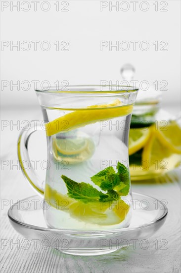 Antioxidant hot drink with lemon and mint in transparent tea pot and glass