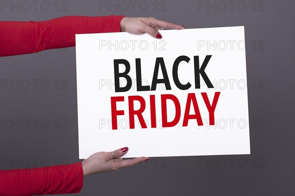 Female hands holding a black friday poster. Studio shot