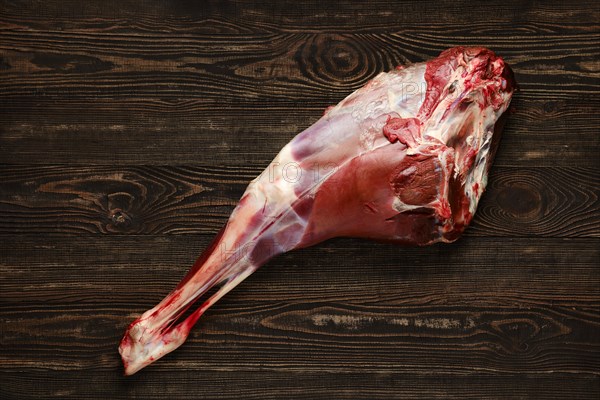 Overhead view of raw deer leg over wooden background