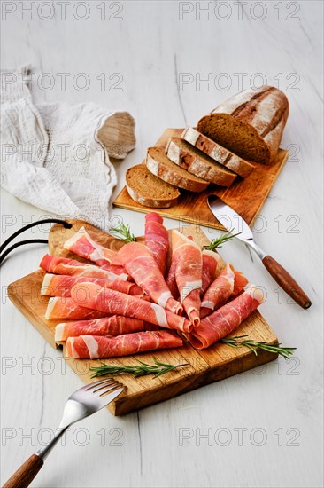 Rolled slices of jamon on wooden cutting board