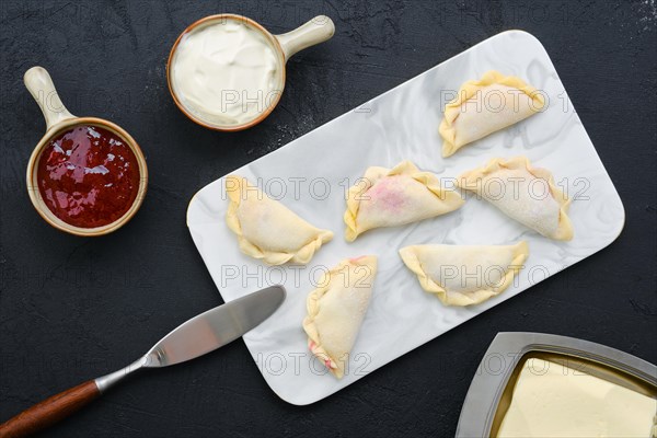 Top view of cherry vareniki on marble serving board with ingredients