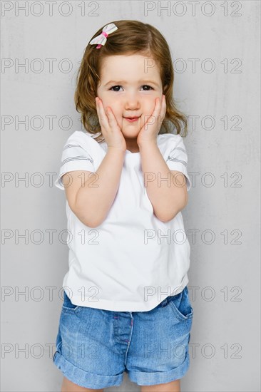 Two years old girl in white t-short and jeans shorts posing in studio