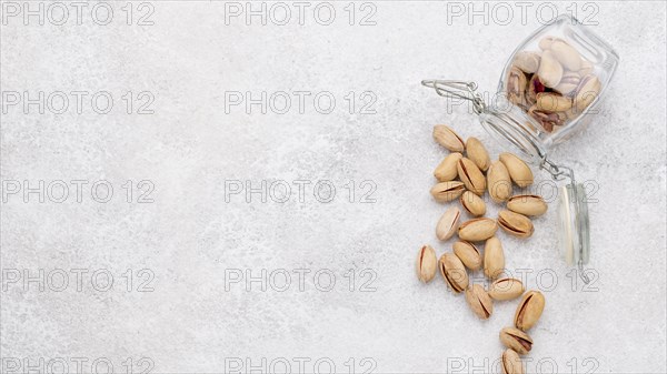 Copy space overturned jar filled with pistachos marble table