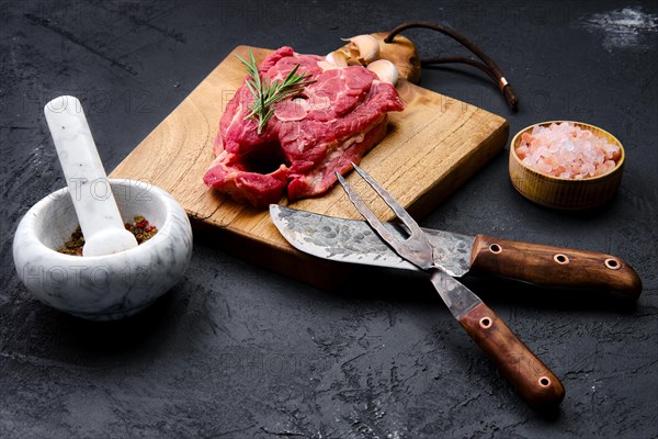 Fresh raw lamb neck on wooden cutting board with herbs and seasoning