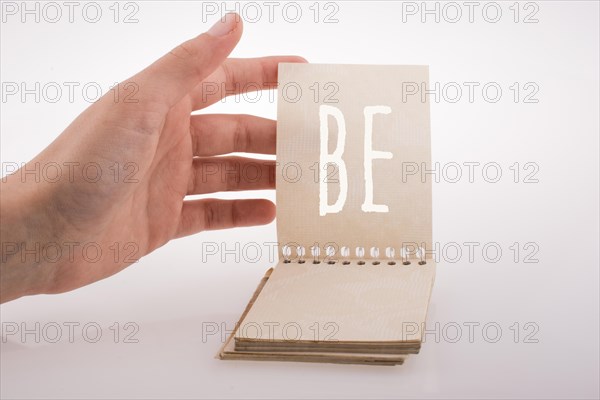 Hand holding notebook with be word on a white background