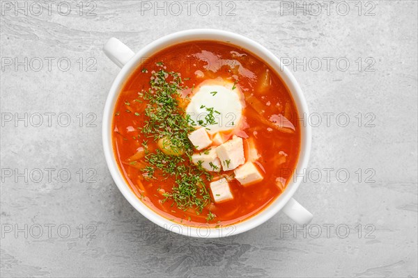 Top view of tomato soup with chicken meat and sour cream