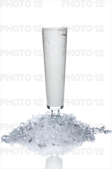 Sling glass with ice-cream and whipped cream on heap of crushed ice isolated on white