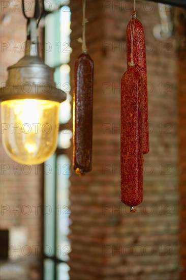 Smoked sausagees hanging on a hook under the ceiling. Photo with shallow depth of field