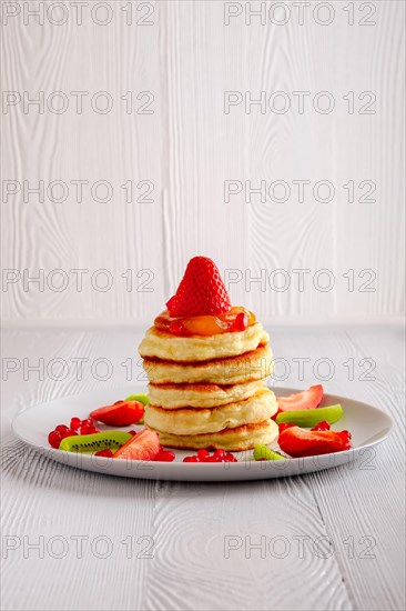 Stack of hot flapjacks served with fresh strawberries and kiwi