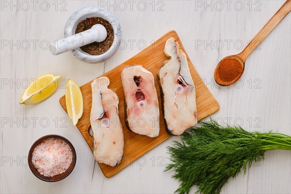 Top view of fresh raw cod steak on wooden cutting board with spice