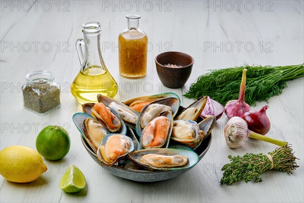 Plate with raw large mussels in half shell with spice on wooden table