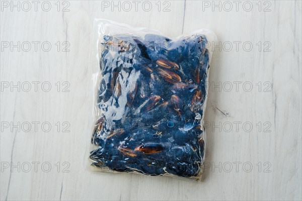 Cooked frozen mussels meat in vacuum packaging on wooden table
