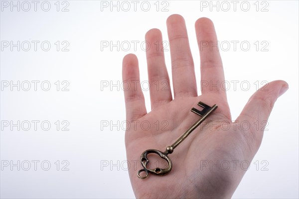 Hand holding a retro styled metal key on a white background