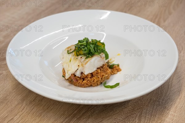 Fried white fish fillet with quinoa porridge on wooden table