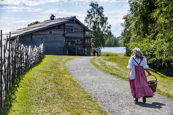 Traditionla dressed woman on her way to a wooden house